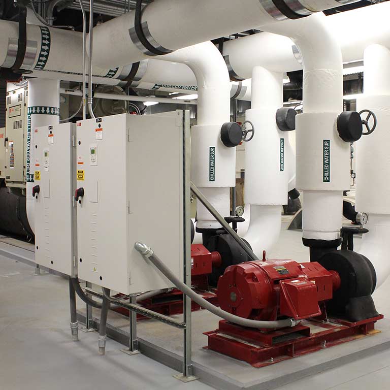 A utility room in a campus building with various water pipes and machinery