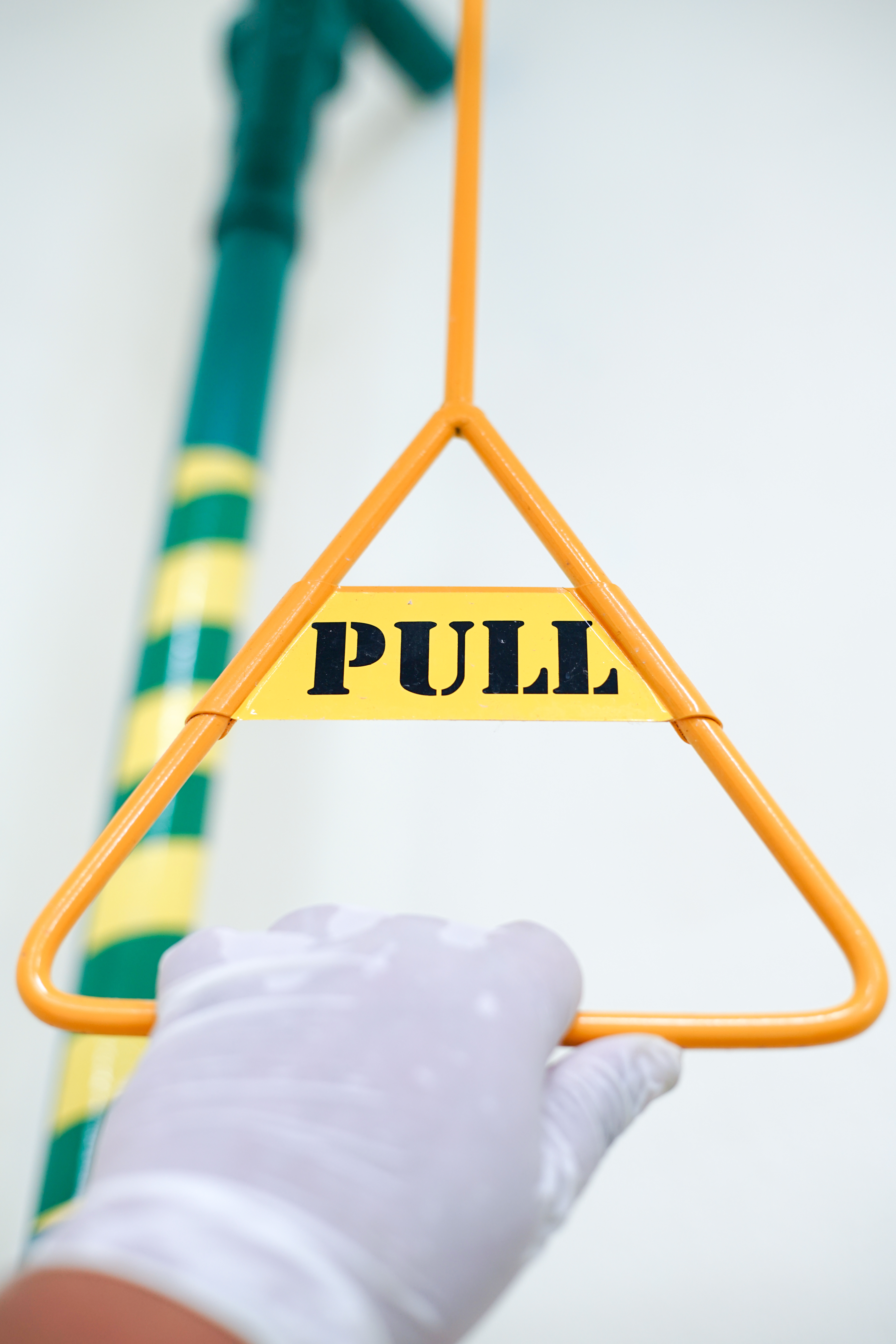 A gloved hand pulling an orange metal triangle