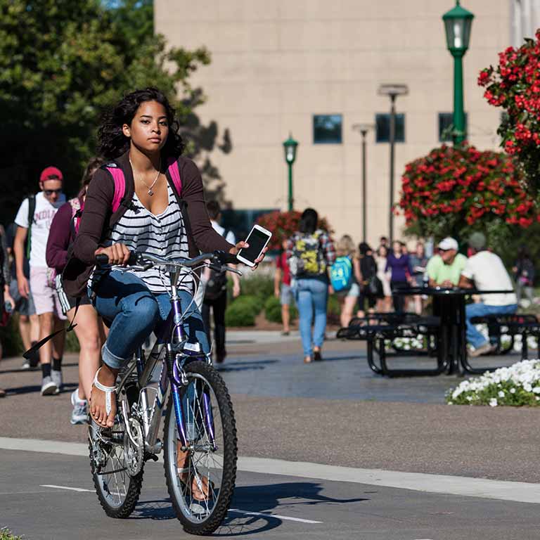 A student rides her bike near the Showalter Fountain on the Indiana University campus.